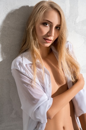 Attractive sexy blonde posing against white wallの写真素材