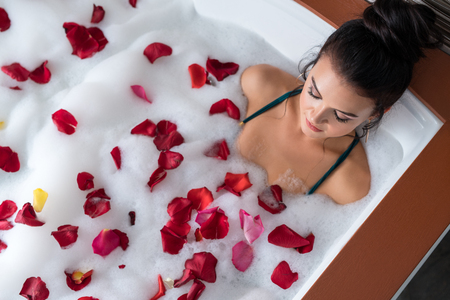 Brunette in hot tub with rose petals top viewの写真素材