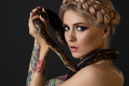 Tattooed blonde with python on black backgroundの写真素材
