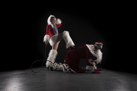 Snow Maiden with whip and Santa on his knees shotの写真素材