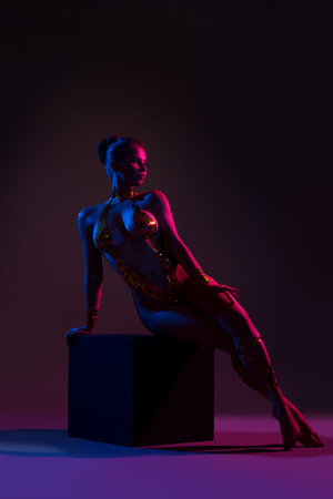 Beautiful nude girl with body art sitting on a cubeの写真素材