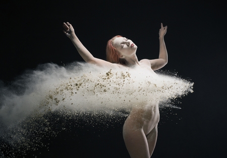 Nude woman dancing gracefully in dust cloud viewの写真素材