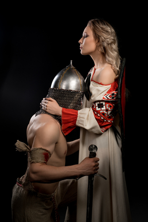 Young viking on his knees before beautiful wifeの写真素材