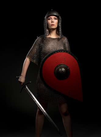 Sexy girl in viking helmet and hauberg with swordの写真素材