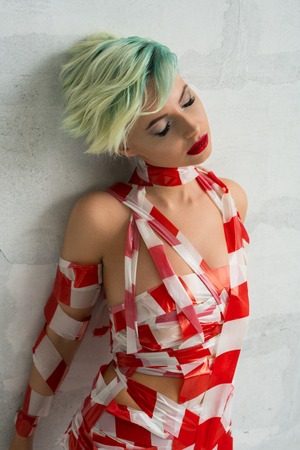 Nude blonde wrapped with red and white scotch tapeの写真素材