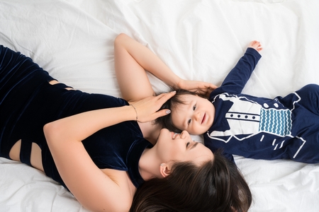 Mother lying in bed with baby boy high angle shotの写真素材