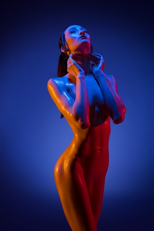 Brunette in the nude in violet light cropped viewの写真素材