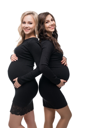 Happy preganant blonde and brunette isolated viewの写真素材