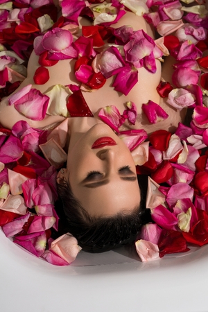 Beautiful brunette having bath with rose petalsの写真素材