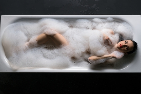 Sensual lady lying in foam in bathtubの写真素材