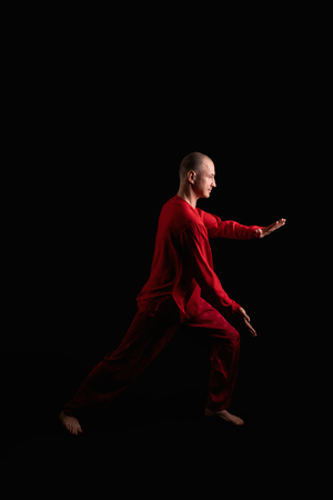 Man in red costume practicing qigong in the darkの写真素材