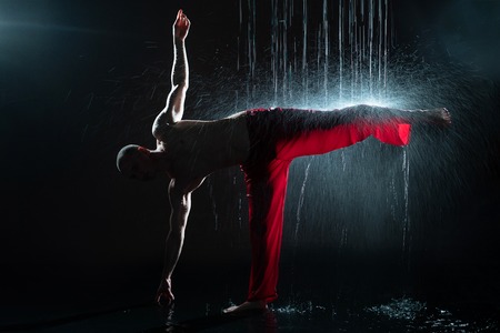 Shirtless man practicing qigong under the rainの写真素材