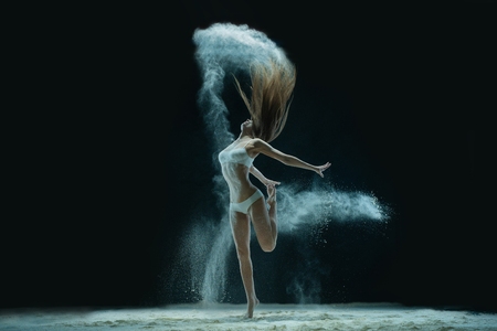 Woman in lingerie dancing in sandy cloudの写真素材