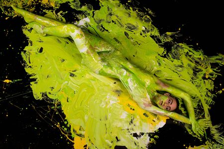Nude girl covered by yellow color shotの写真素材