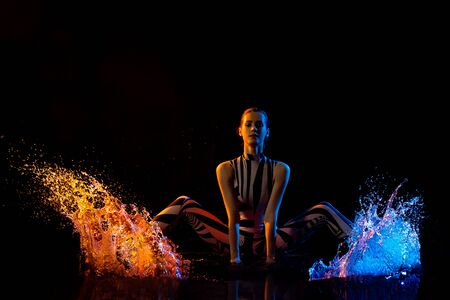 Fitness model shot in water drops in the darkの写真素材