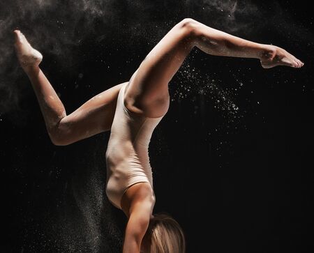 Slender blonde dancing in white dust studio shot