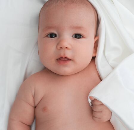 Baby boy lying on white linen close up studio shotの写真素材