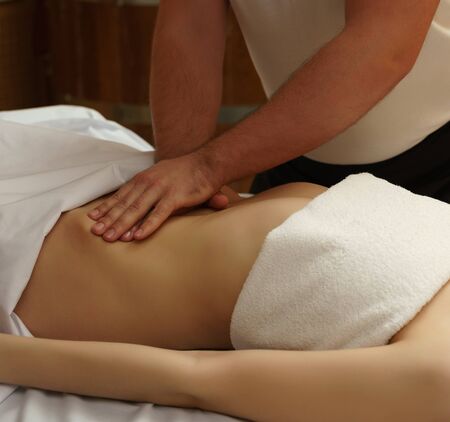 In spa center. Masseur massaging girls bellyの写真素材