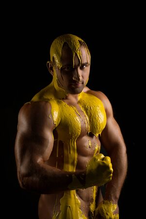 Athletic man in yellow paint shotの写真素材