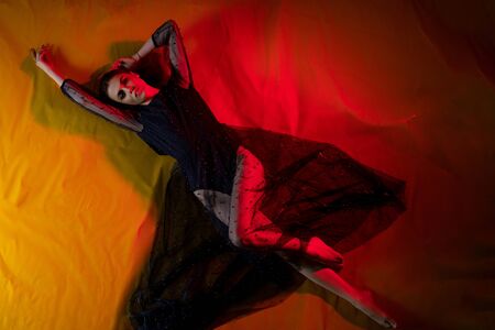 Beautiful girl in black dress lying on the floorの写真素材