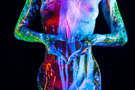 Woman body with ultraviolet color bodyart and hands in heart symbolの写真素材