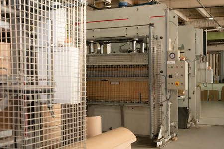 Row of industrial machines for chipboard production installed in workshop of modern lumber furniture...