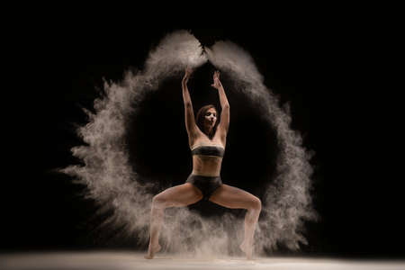 Slim female dancer throwing dust in air