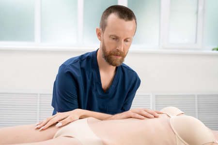 Bearded osteopath working with crop woman
