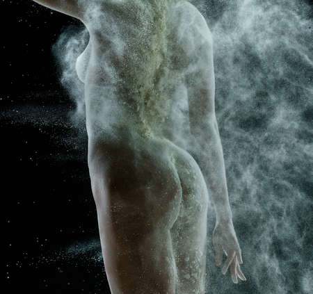 Nude girl in a cloud of white dust studio portraitの写真素材