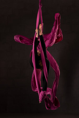 Flexible teen doing aerial silks trick on fabricの写真素材