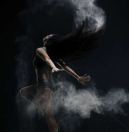Brunette jumping gracefully in dust cloud viewの写真素材