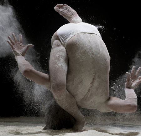 Male gymnast exercising in white dust cloud shotの写真素材