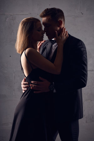 Loving couple teasing each other in black female dress and male black suitの写真素材