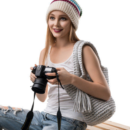 Charming smiling young woman in hat with photo camera and handbag on palletsの写真素材