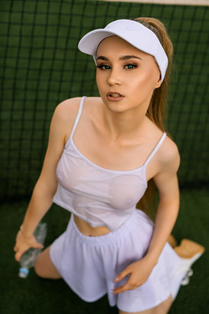 Female Tennis Player Posing With Water Bottle on Court During Daylightの写真素材