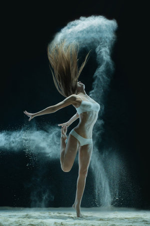 Woman in lingerie dancing in sandy cloudの写真素材