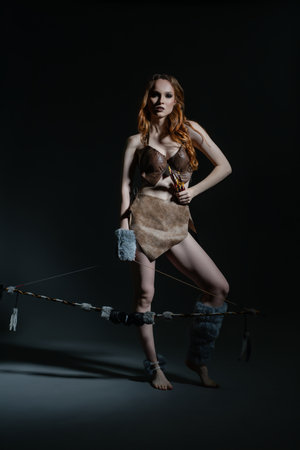 Female with red hair dressed in prehistoric clothing poses dramatically indoorsの写真素材