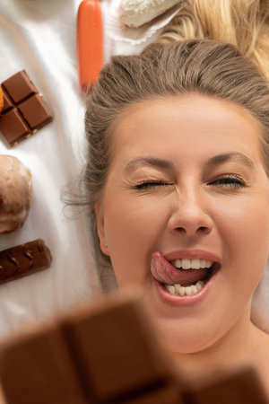 Woman enjoying chocolate with a playful expression on a cozy blanket