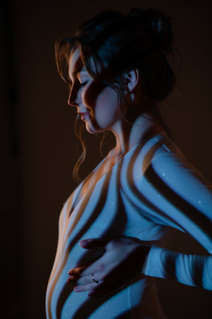 Beautiful pregnant woman in lingerie poses gracefully with soft lightingの写真素材