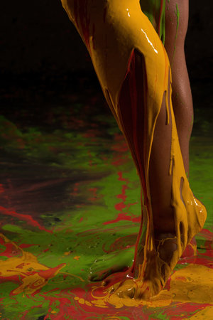 Colorful paint pouring over a leg during an artistic performance in a studioの写真素材