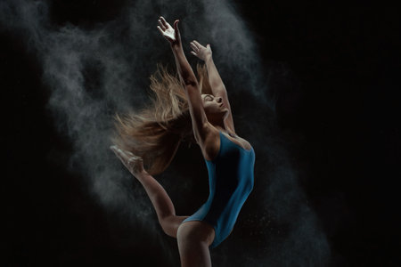 Dancer in motion creating dynamic shapes in dark studioの写真素材