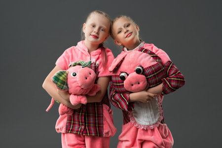 Two children dressed in pig costumes holding plush toys in playful poseの写真素材