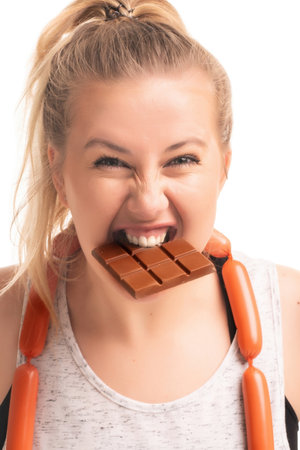 Woman playfully holds chocolate bar with sausage necklace in studio