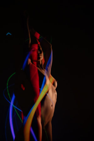 Woman posing with colorful light projections in a dark settingの写真素材