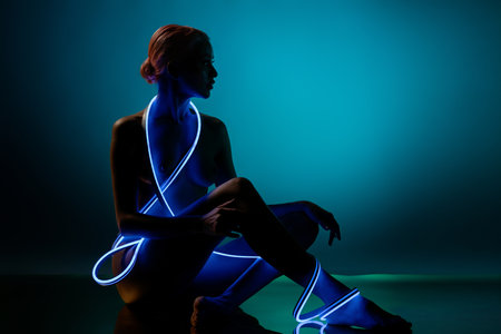 Woman posing gracefully with blue light accents in a creative art settingの写真素材