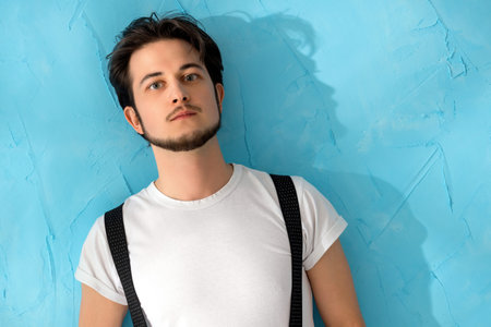Young man posing with confidence against a vibrant blue background