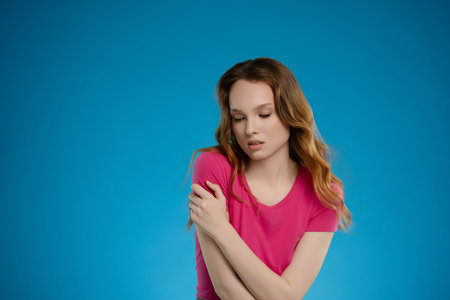 Woman poses in a studio setting with a blue backdrop, expressing a range of emotions in her thoughtful demeanorの写真素材