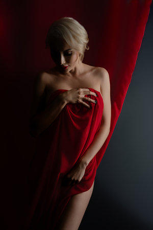 Elegant woman draped in flowing cloth poses gracefully in studio settingの写真素材