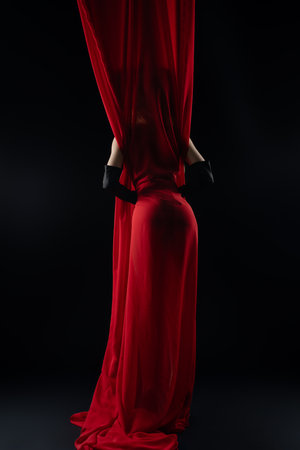 Model posing elegantly behind flowing red fabric in a dramatic settingの写真素材