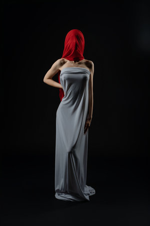 Model poses in a dramatic fashion casting with a striking red headscarfの写真素材